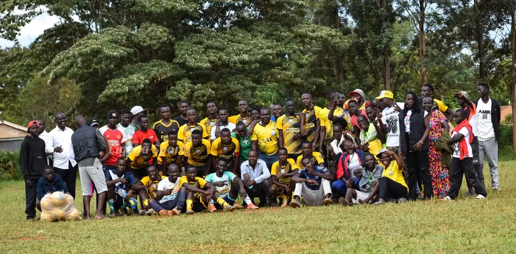 A large group photograph of Ligega Sports players, coaches and supporters together on the pitch.