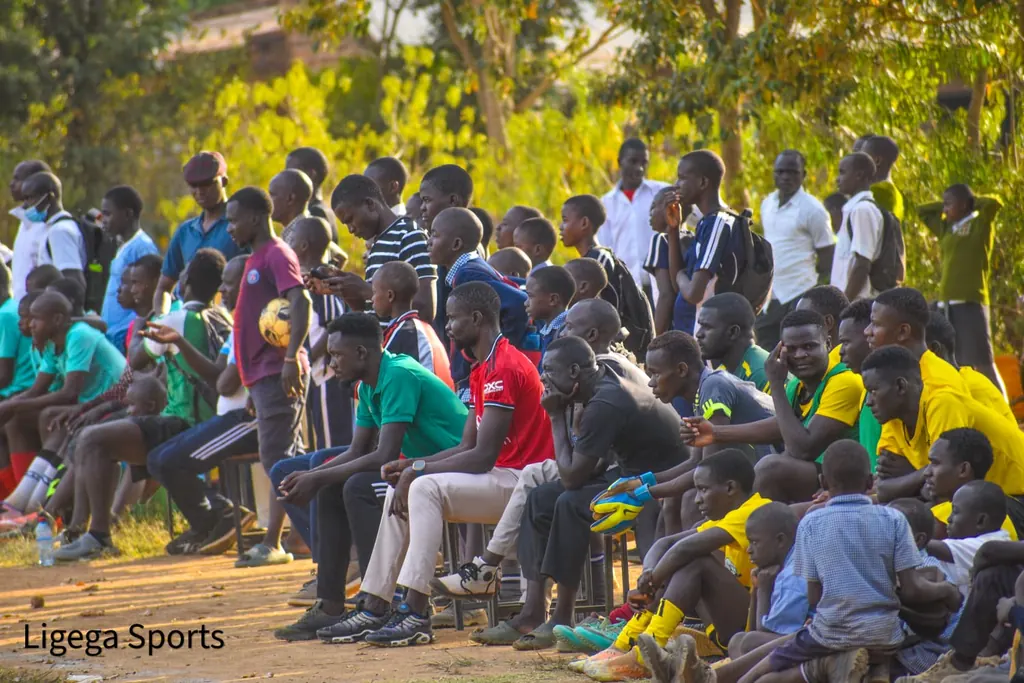 Ligega Sports supporters seated and standing along the touchline watching a match.