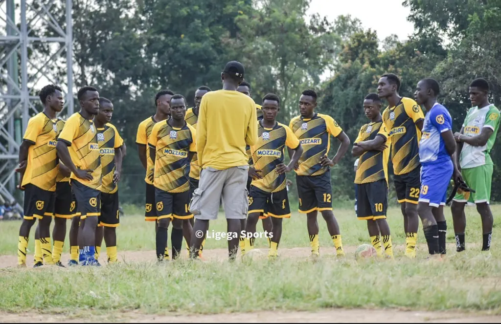 The Ligega Sports squad in the club's yellow and black kit, gathered on the pitch for a team talk.
