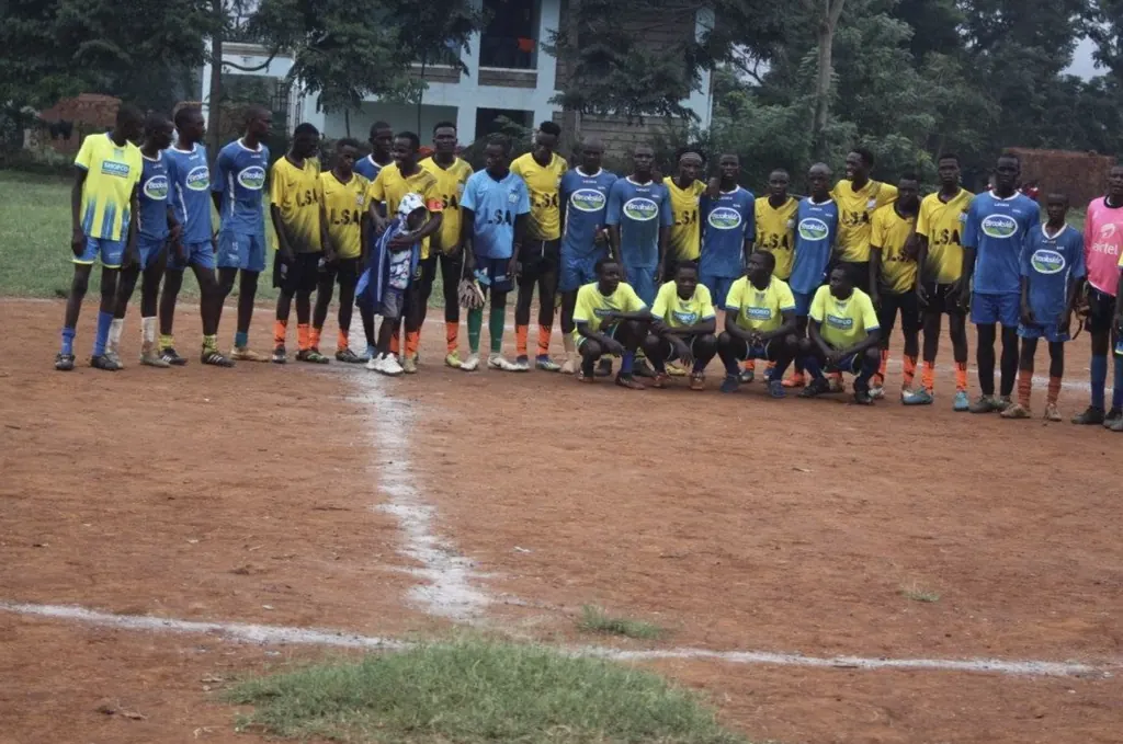 The Ligega Sports Stars squad lined up across the pitch in blue and yellow kit before a match.
