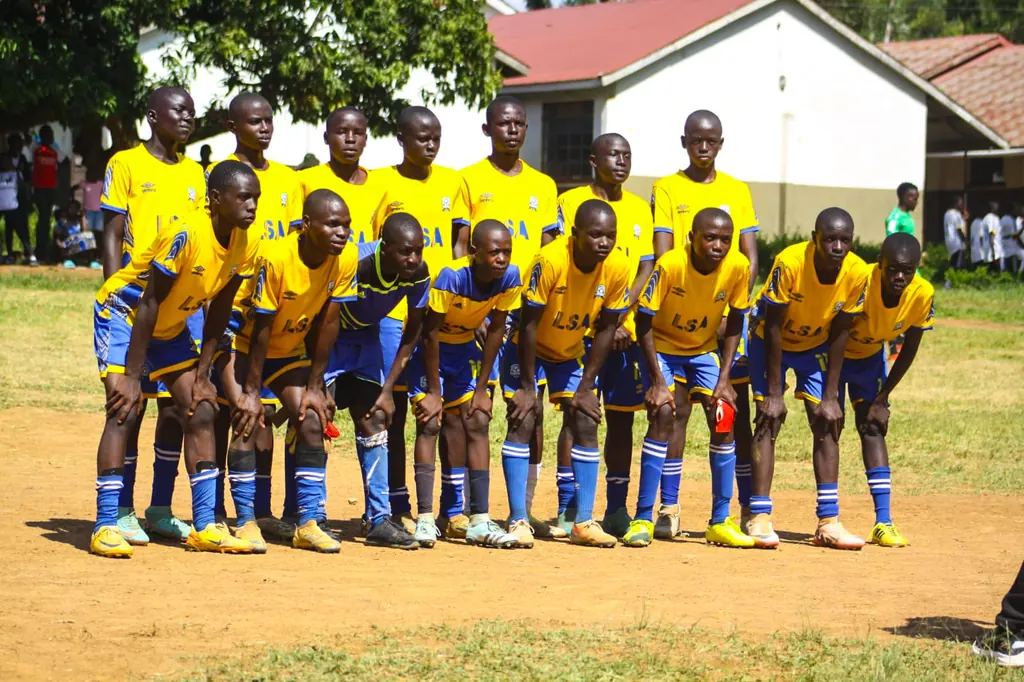 The Ligega Sports under-15 squad in yellow and blue kit with their goalkeeper in black, photographed together on the pitch.